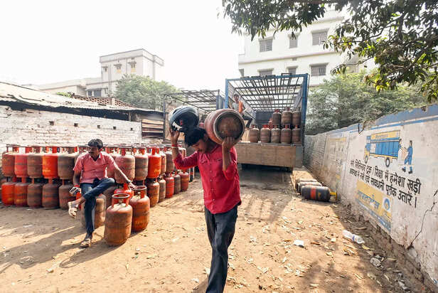A man unloads petroleum gas (LPG) cylinders from a tempo am...