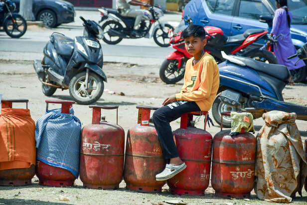 A boy sits on a gas cylinder to refill LPG cylinders outsi...