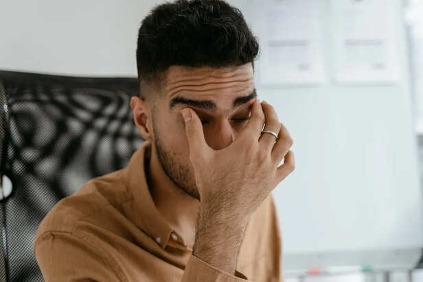 Young professional rubbing eyes while working on laptop