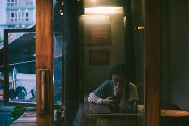 Person Sitting Alone While Looking at a Phone