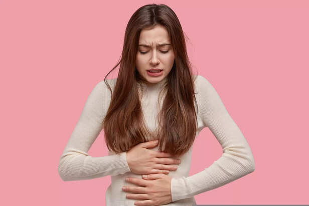 "Young Woman Experiencing Menstrual Discomfort or Cramps on a Pink Background"